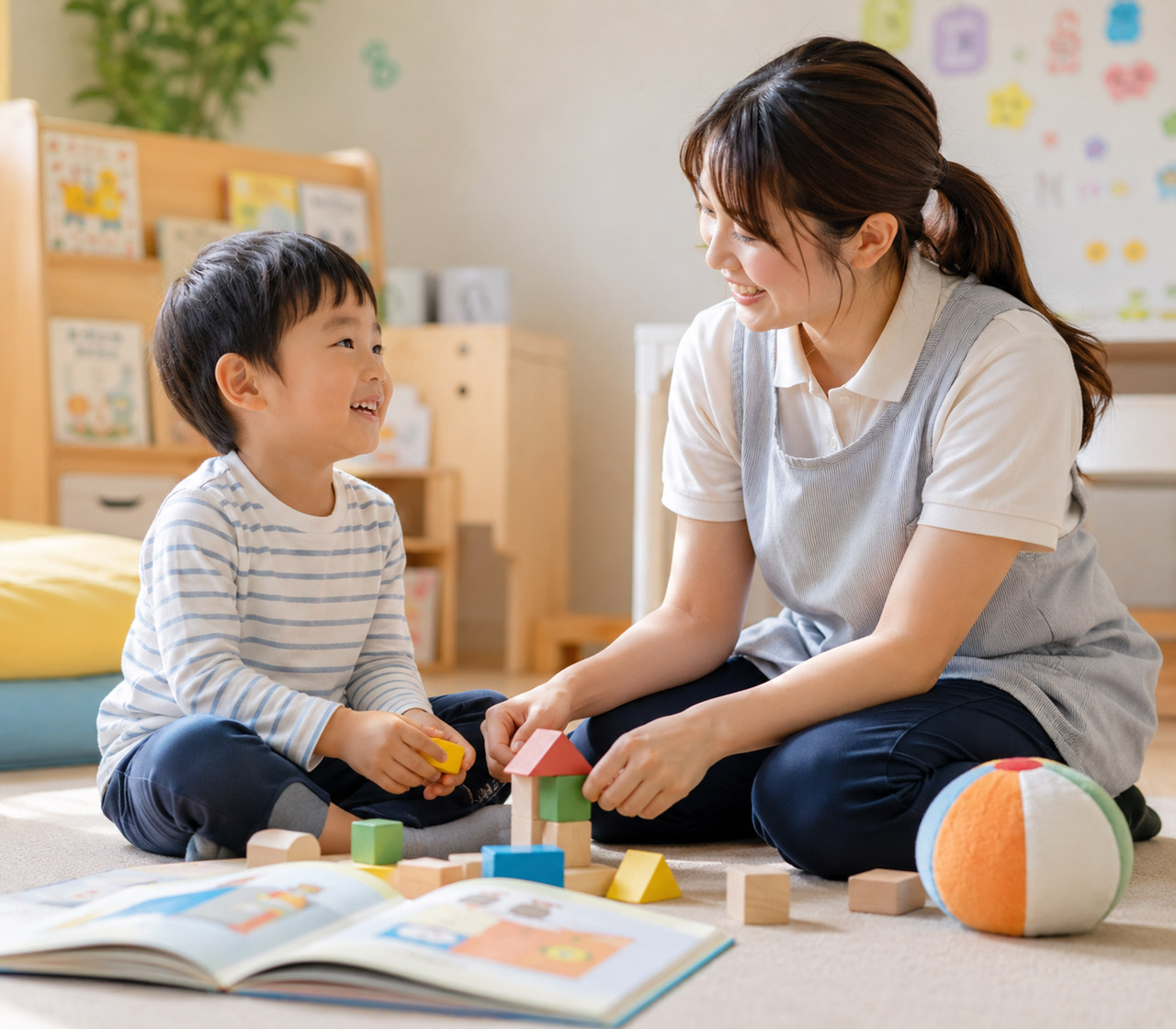 スタッフが子どもと床に座って一対一で関わっている場面